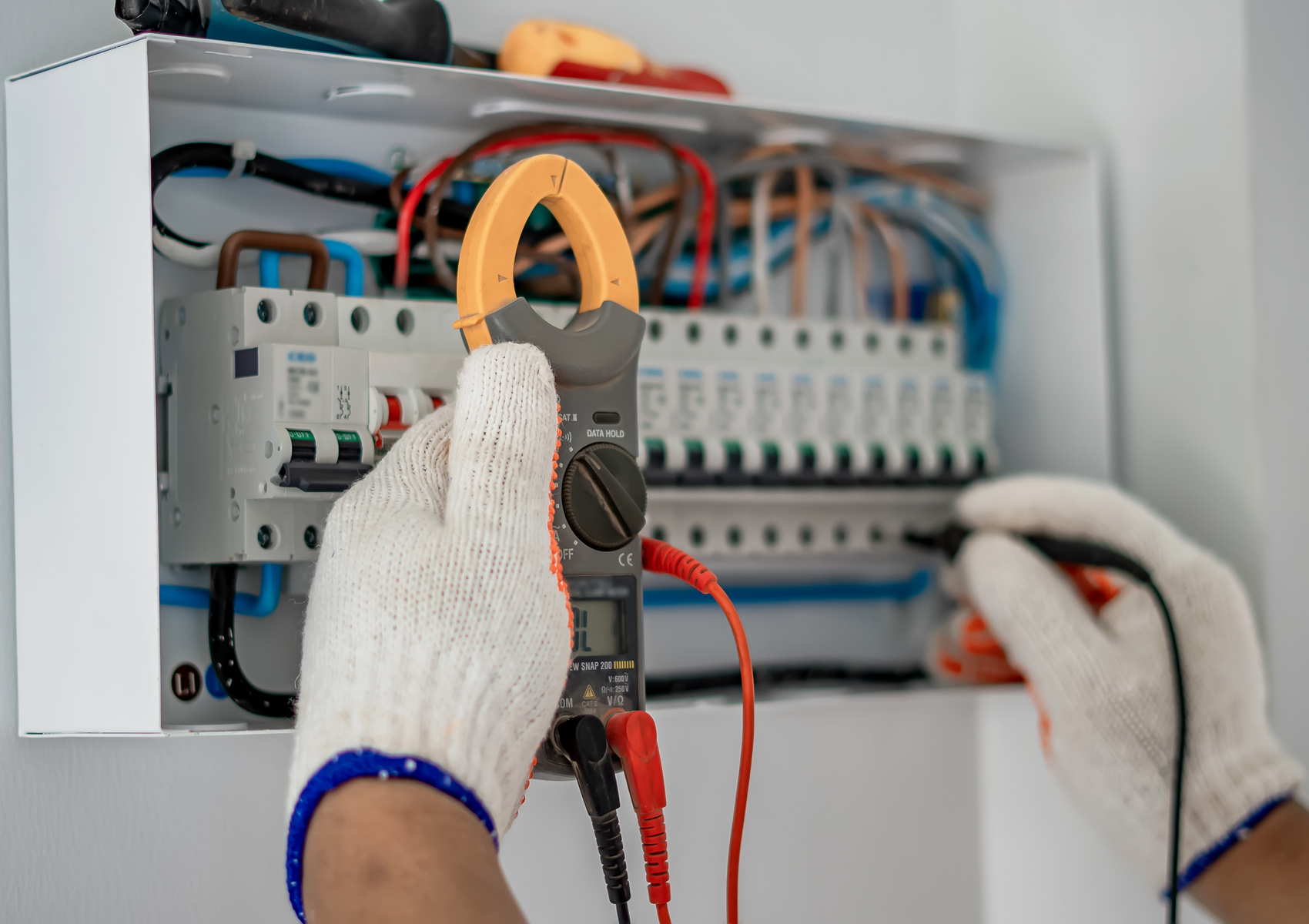 The Importance of an EICR in the Workplace 10 A man in gloves inspects an electrical panel while conducting a safety report for a property’s electrical installation.